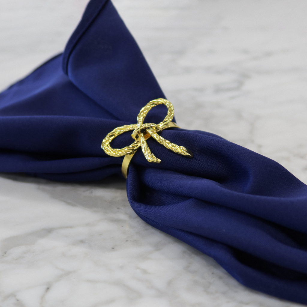 https://cdn.shopify.com/s/files/1/0042/0390/5136/files/Gold-Rope-Bow-Tie-Napkin-Ring-lifestyle.png?v=1765465142